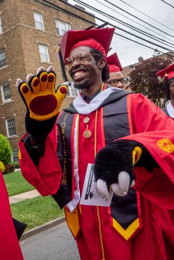 graduating student performer wearing Deacon the Bear's plush paws