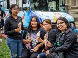 Students and parent smile holding ice cream cones in front of an ice cream truck.