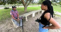 Daisha Robinson speaking with a local man under the shade of a tree
